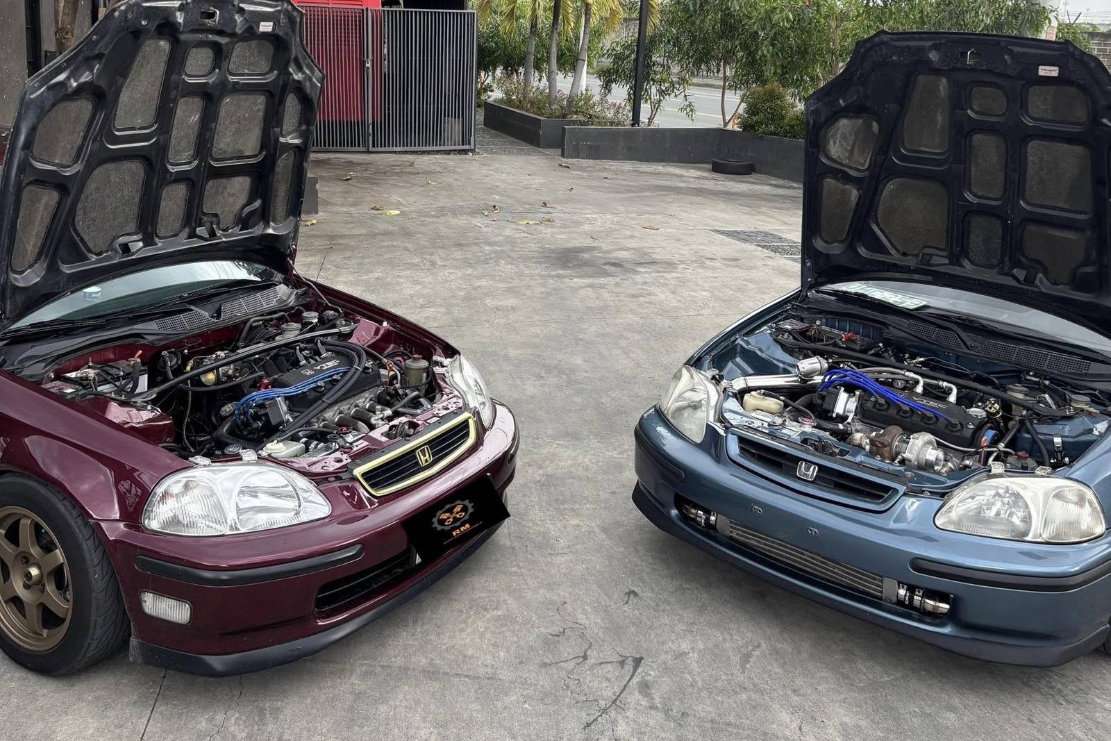 Two Honda Civics with their hoods open at the RM Auto shop